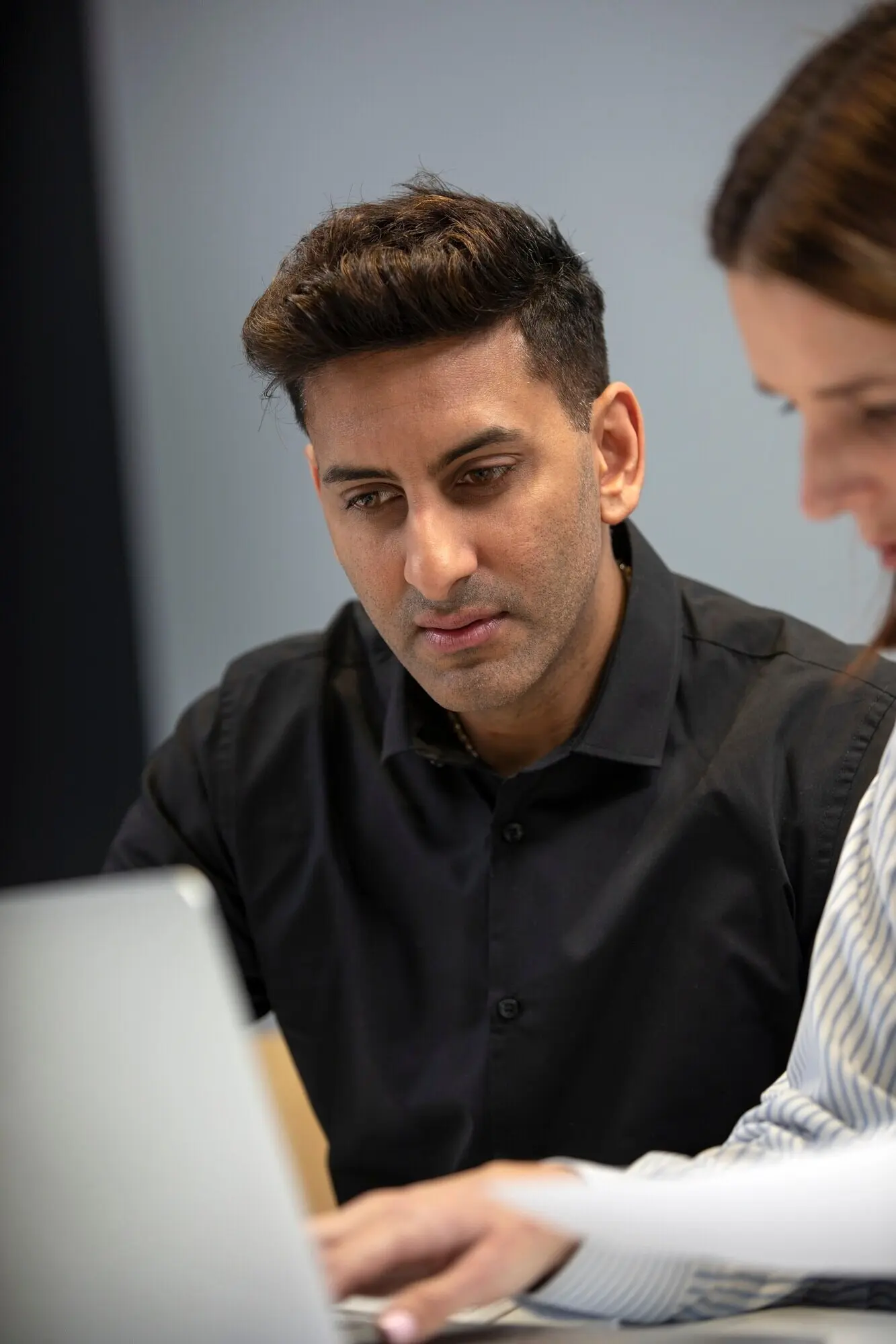 Eine Frau und ein Mann arbeiten mit einem Laptop.