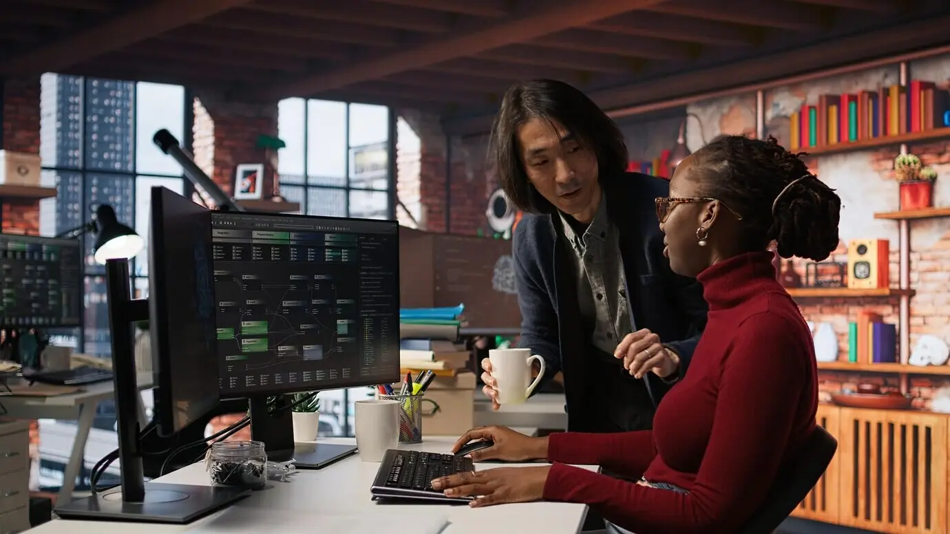 Ein CTO-Vorgesetzter in einem KI-Startup bringt einem müden Mitarbeiter Kaffee.